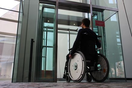 Eine Person in einem Rollstuhl vor einem Aufzug im OZEANEUM